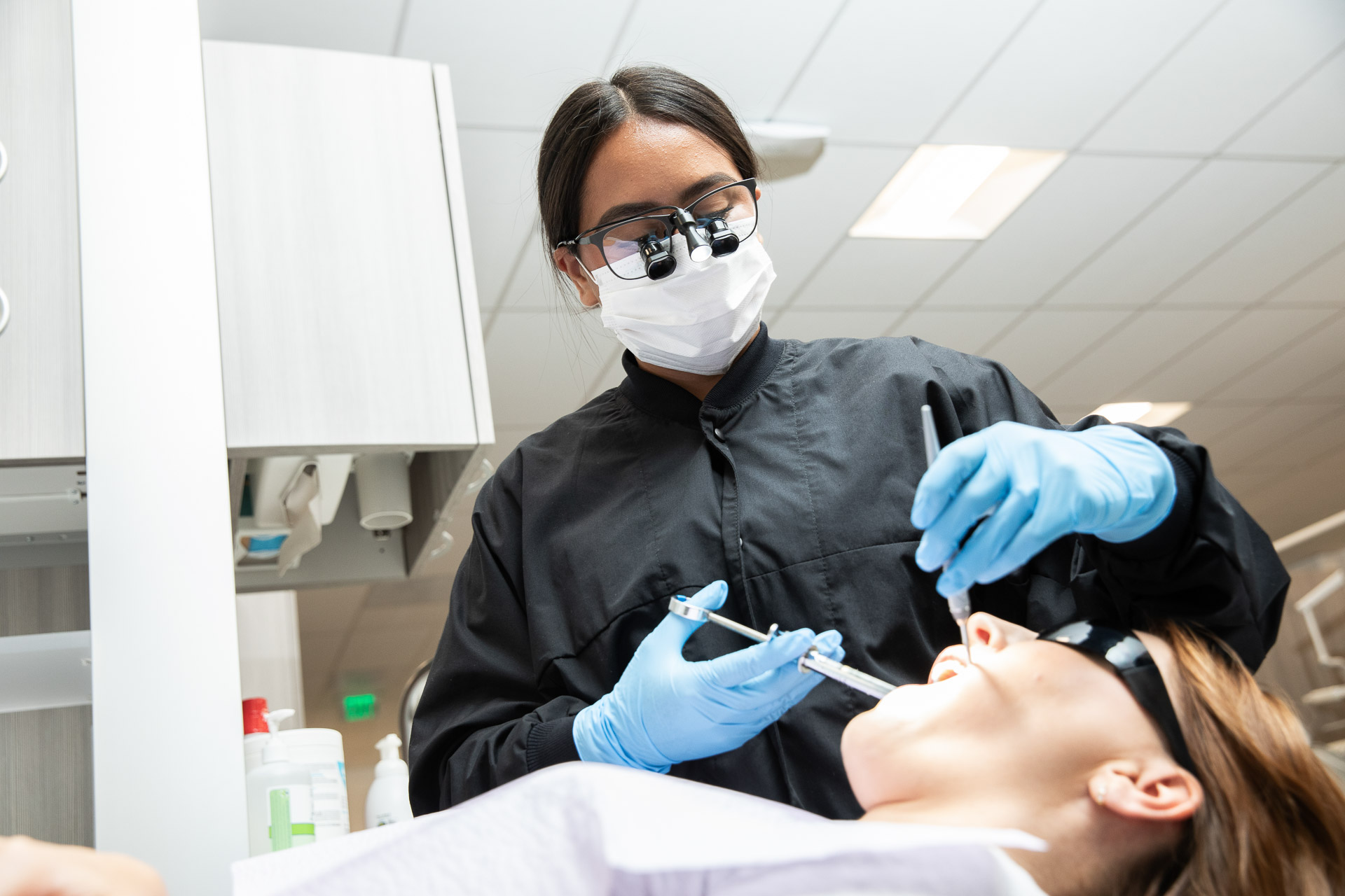 dental hygiene student in PPE assisting a patient