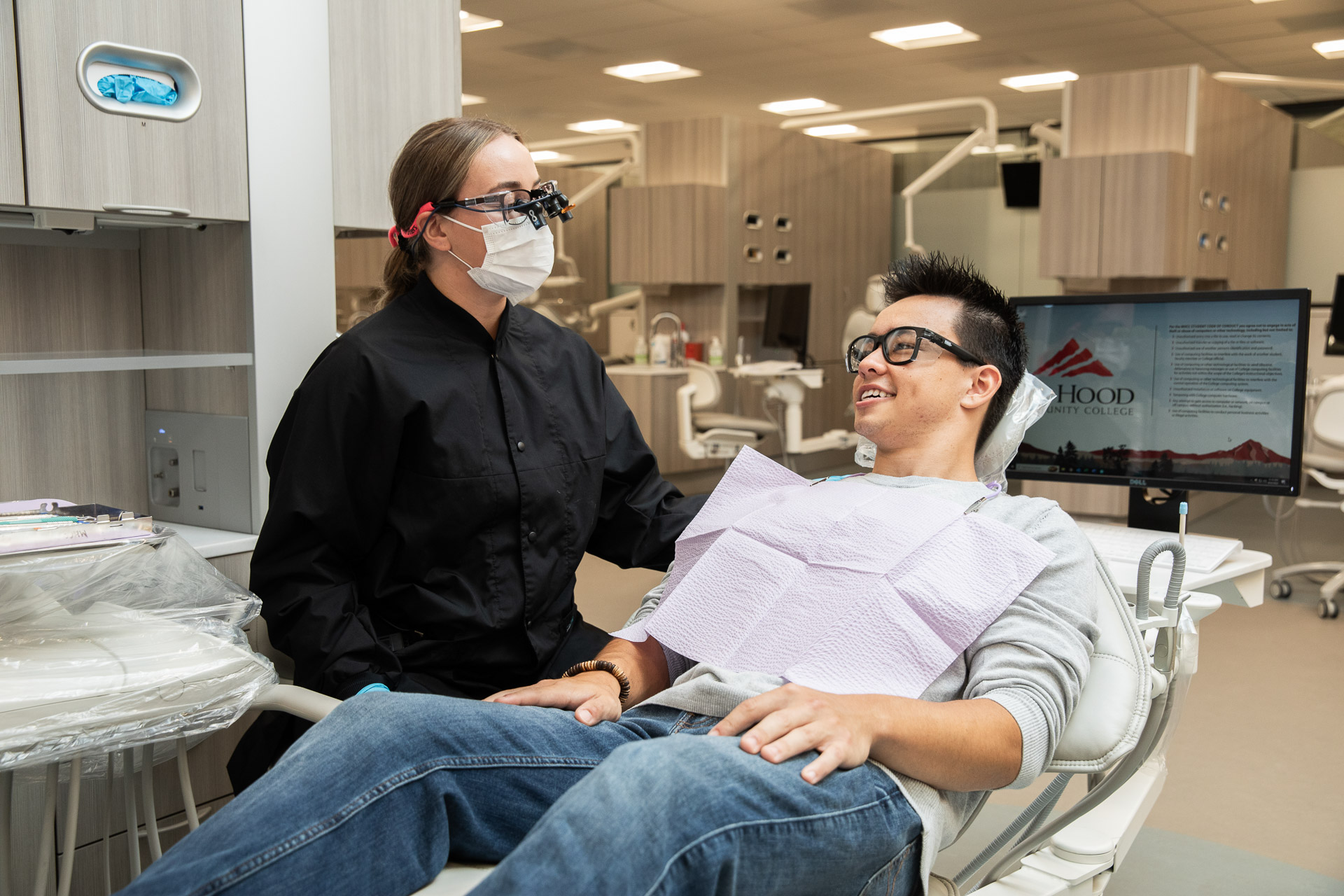 Dental hygiene students with a person in a dentist chair during an exam