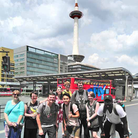 Students in a busy section of the city with a tower in the background